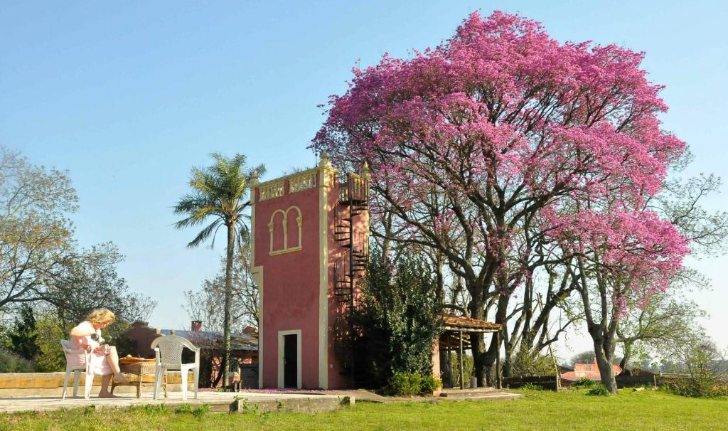 乌拉圭河畔康塞普西翁Estancia La Titina, Posada y Reserva Natural的站在一棵树旁的一位女士,花朵粉红色