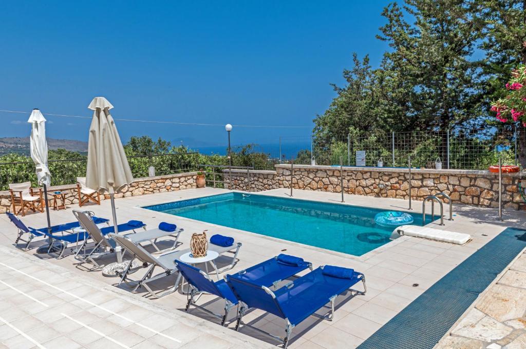 普林斯Villa Despina的一个带椅子和桌子的游泳池以及一把遮阳伞