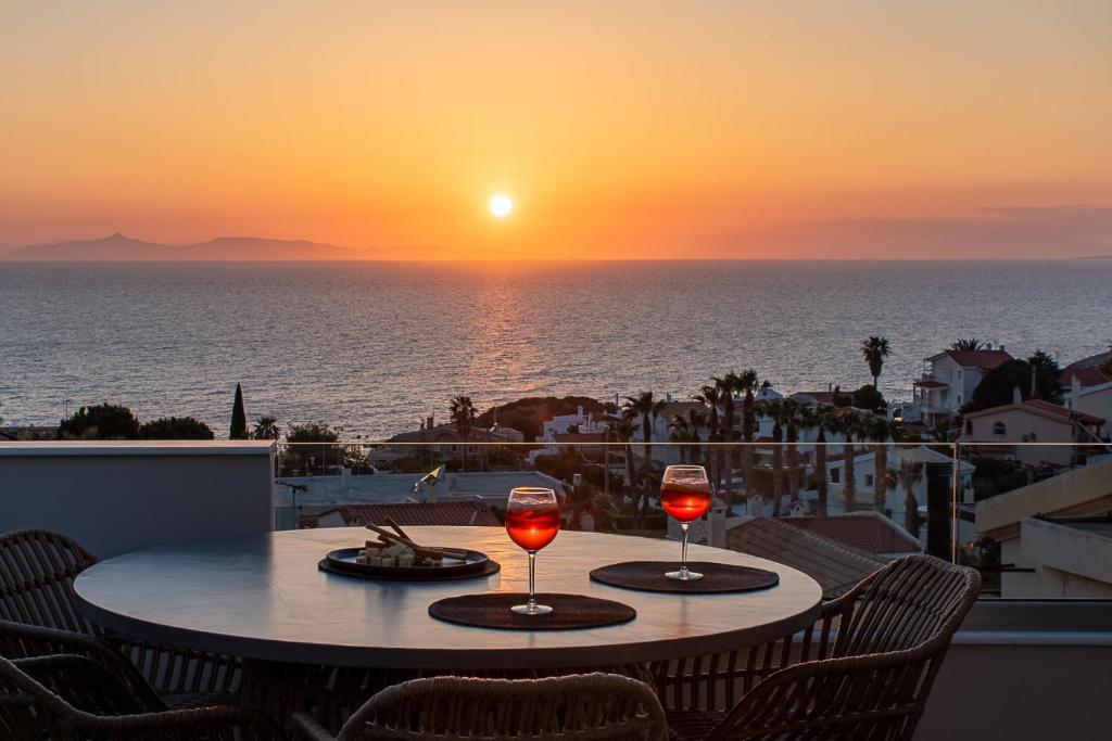 苏尼翁LazySun的阳台上的一张桌子和两杯葡萄酒,享有日落美景
