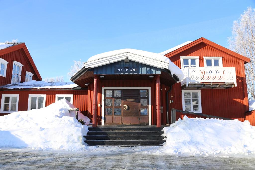 赫马万Hemavans Wärdshus的前面有雪的红色建筑