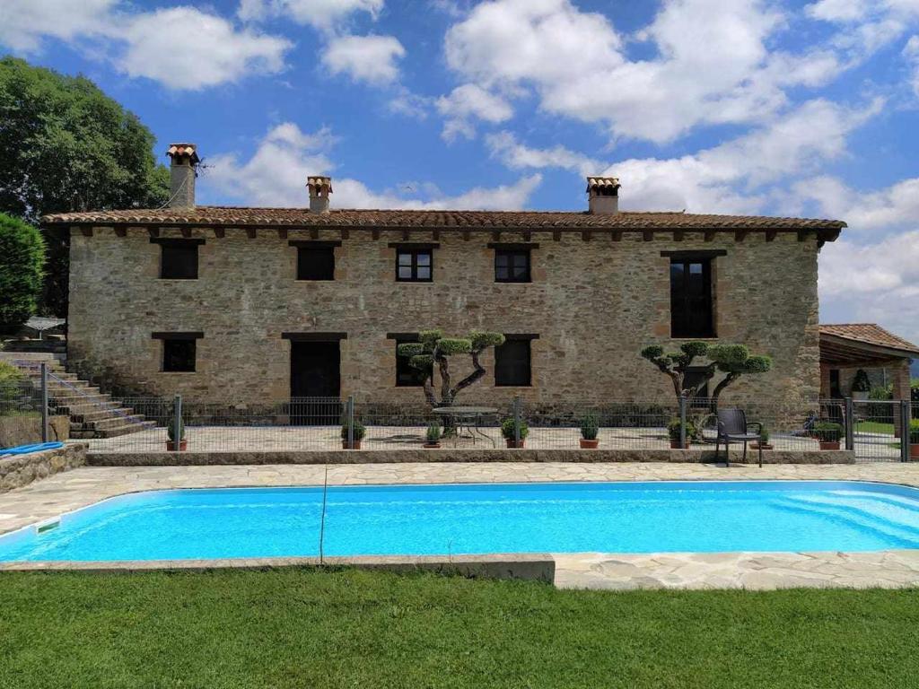 MierasMas Planella Casa Rural的一座石头房子,前面设有一个游泳池