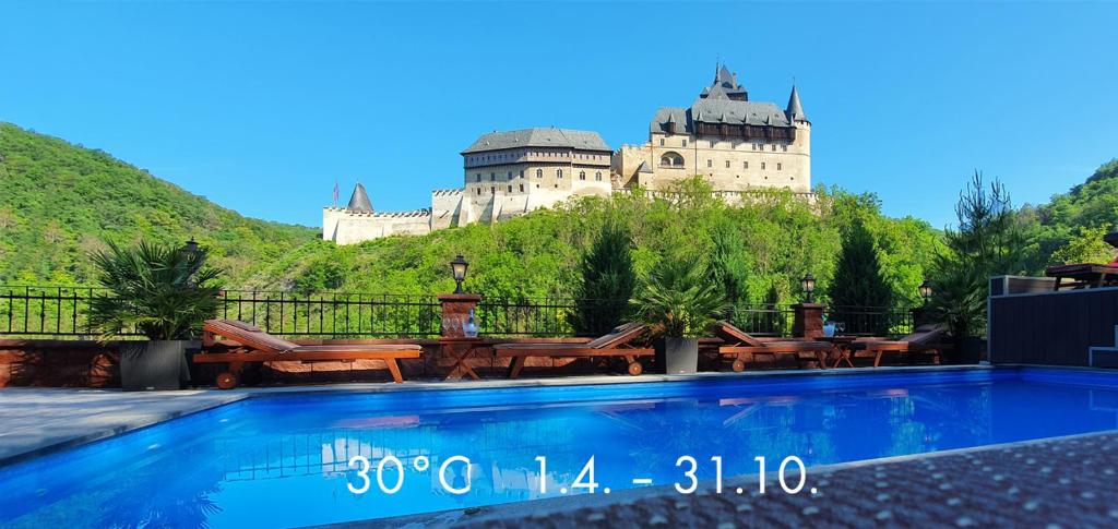 卡尔施泰因Hotel Karlštejn & SPA的山丘上的城堡,前面有一个游泳池