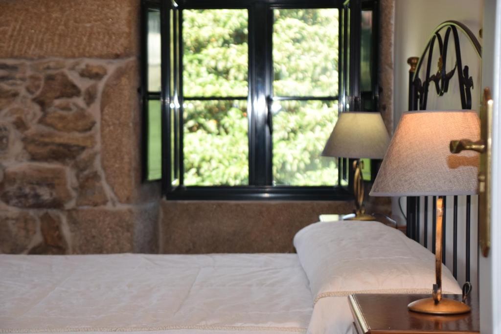 布埃乌Casa Videira - Hotel rural cerca del mar的一间卧室配有一张带两盏灯的床和一扇窗户。