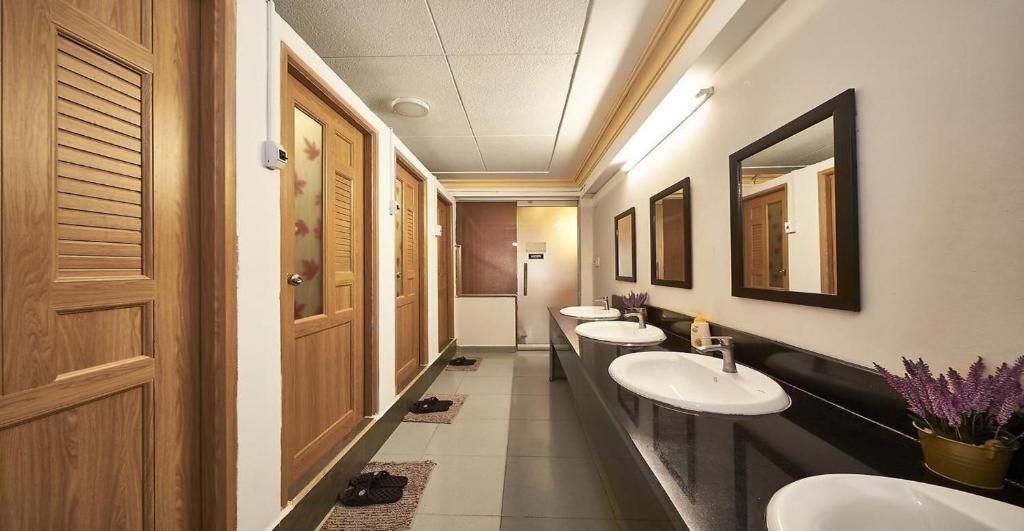胡志明市Alleyway Hostel的浴室设有3个水槽和一排镜子