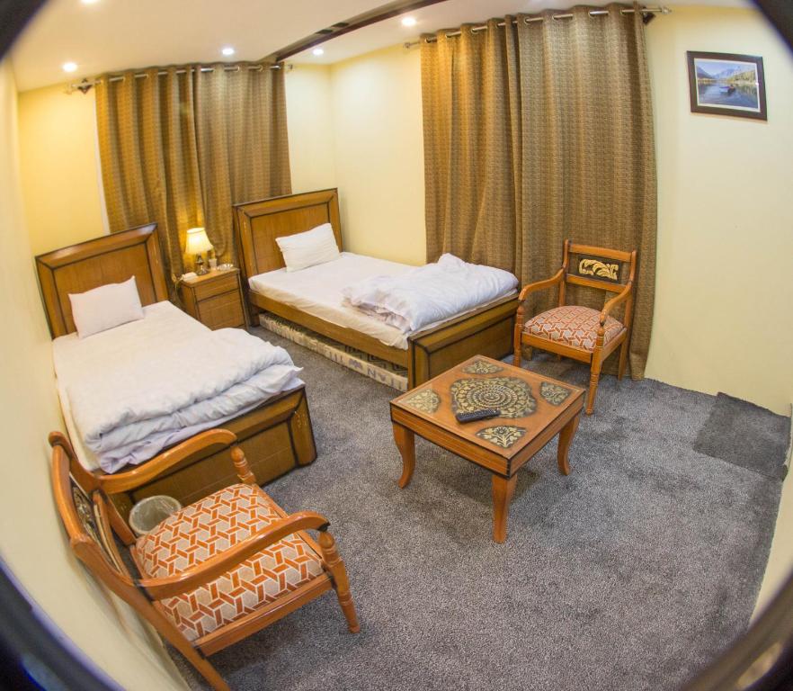 锡卡都Ringchan Guest House & Restaurant的一间设有两张床和一张桌子及椅子的房间