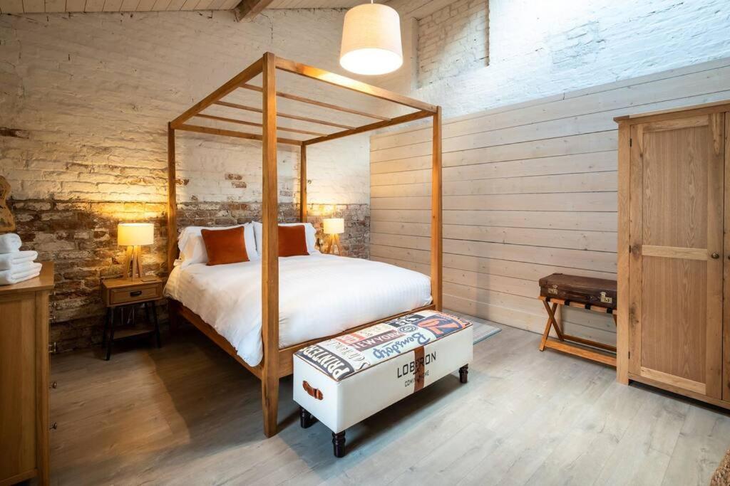 卡斯尔贝灵汉The Mews -- Luxury Stay at Bellingham Estate的一间卧室设有天蓬床和木墙