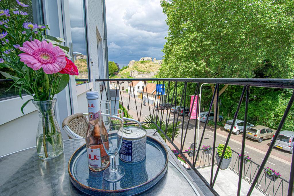 法尔肯堡Logement viphouse Valkenburg的阳台上的桌子上装有一瓶和花瓶