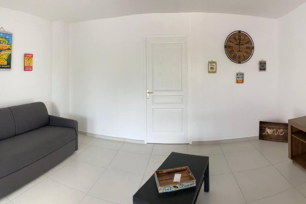勒拉芒坦KAZ'ANTILLAISE APPT AVEC PISCINE TI MAEVA 3/4P. LE LAMENTIN的客厅配有沙发和墙上的时钟