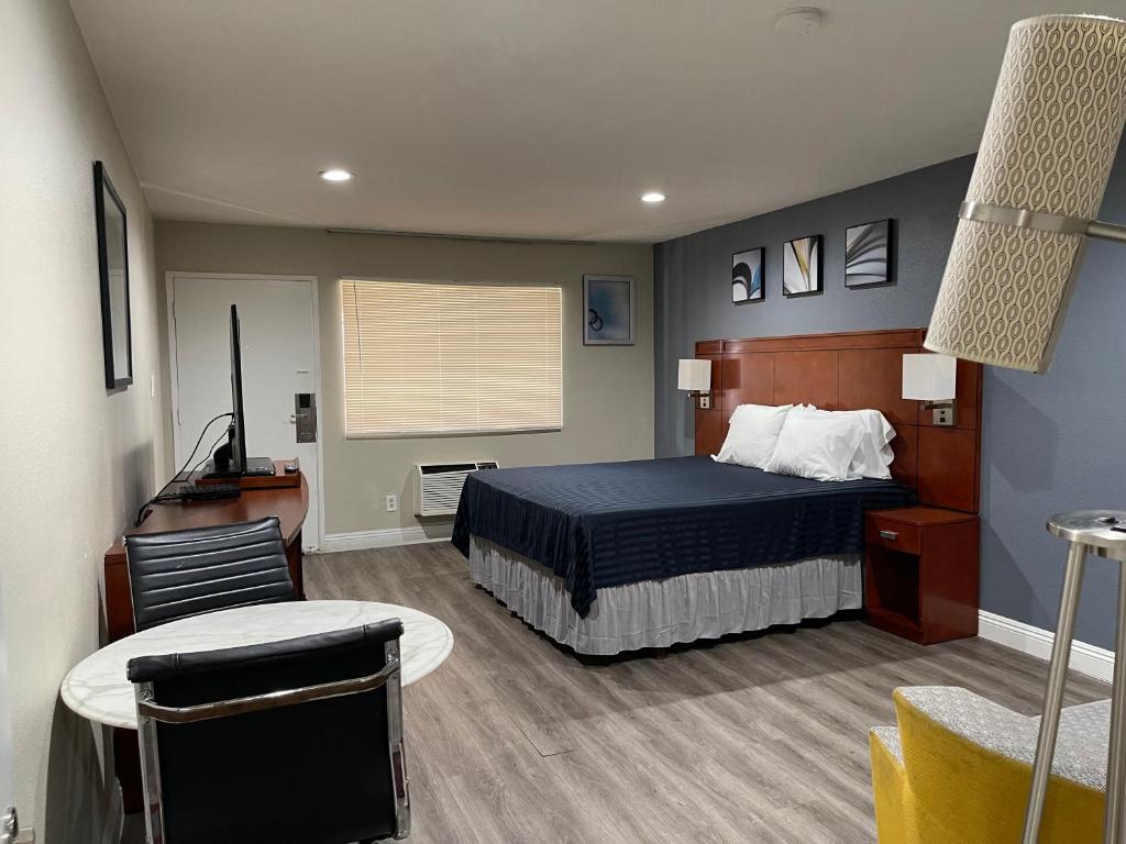 塔斯廷Bel Air Motor Hotel的卧室配有1张床、1张桌子和1把椅子