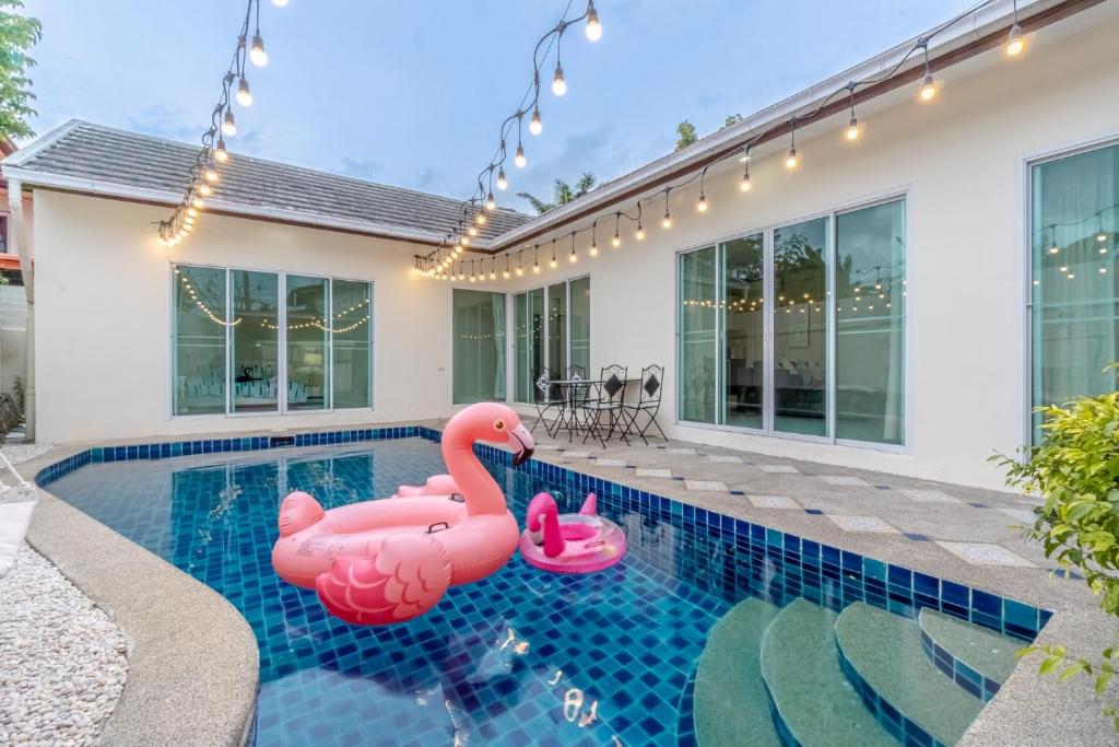 农布Peacock Pool Villa的一座房子的游泳池里有两个粉红色的充气火烈鸟