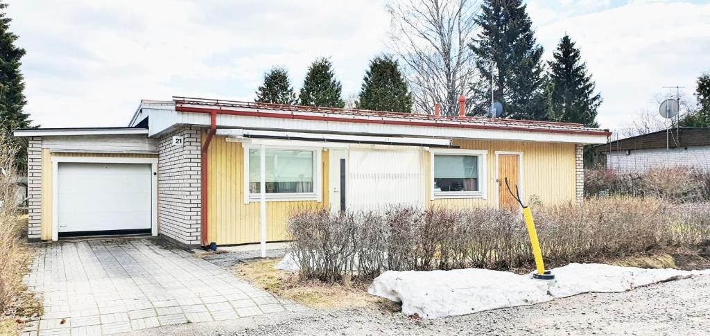 拉彭兰塔Saimaa home的一座黄色的小房子,设有车库