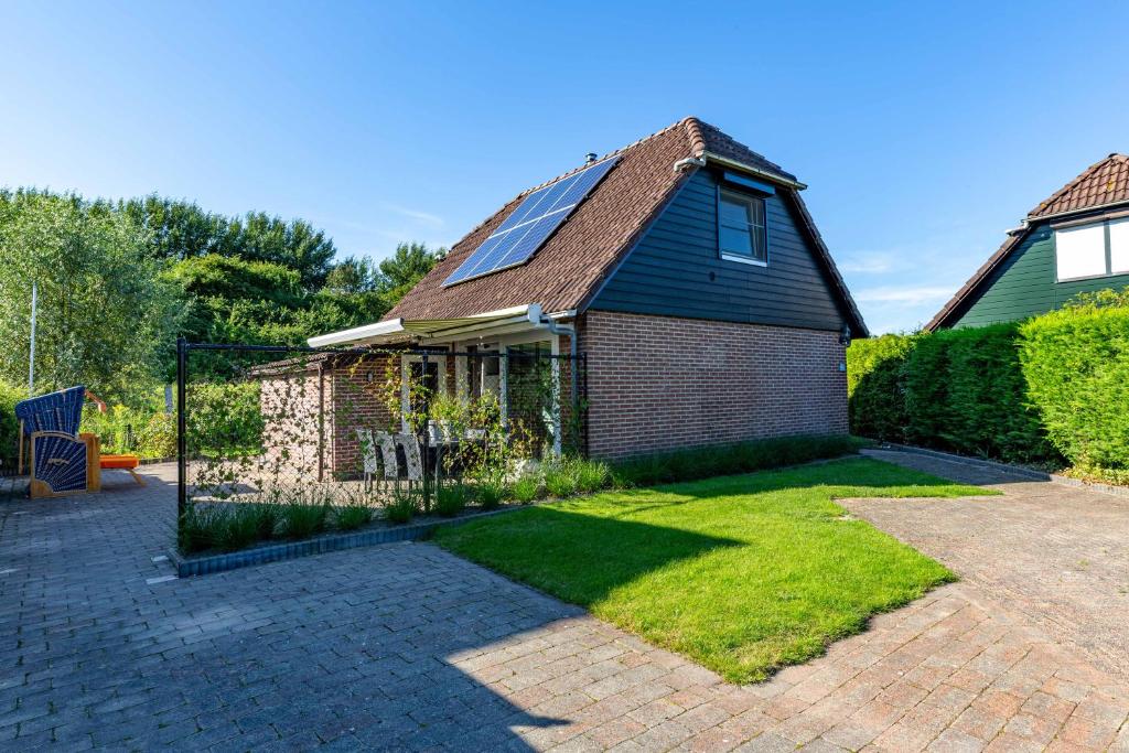 WolphaartsdijkVeerse Meer Lodge的一座带太阳能屋顶和庭院的房子