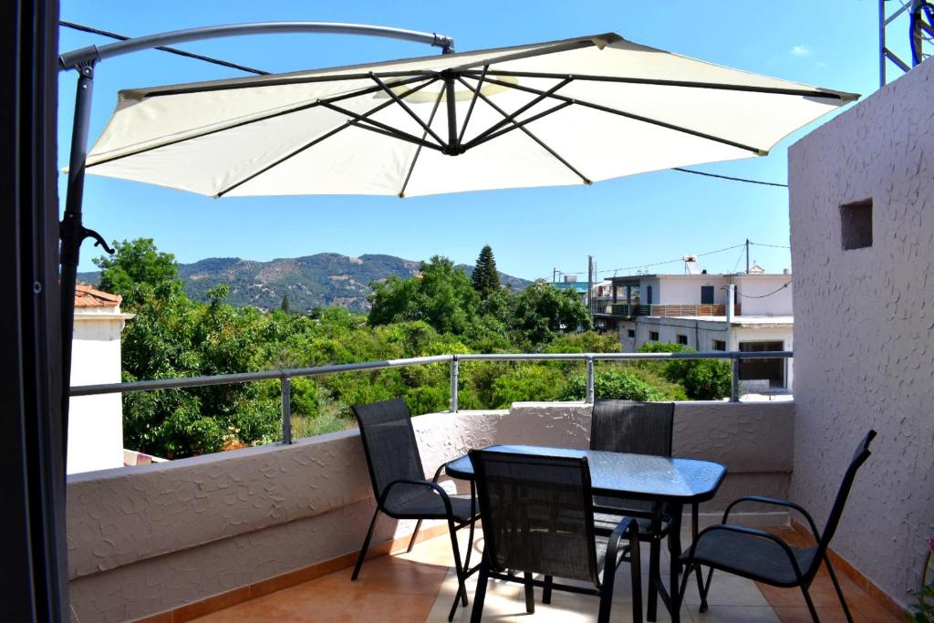 普拉塔尼亚斯S&G HOME的阳台配有桌椅和遮阳伞