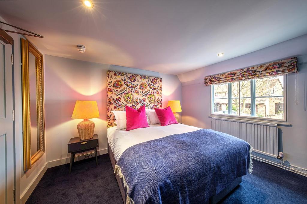 Great WilbrahamThe Carpenters Arms的一间卧室配有带粉红色枕头的床和窗户。