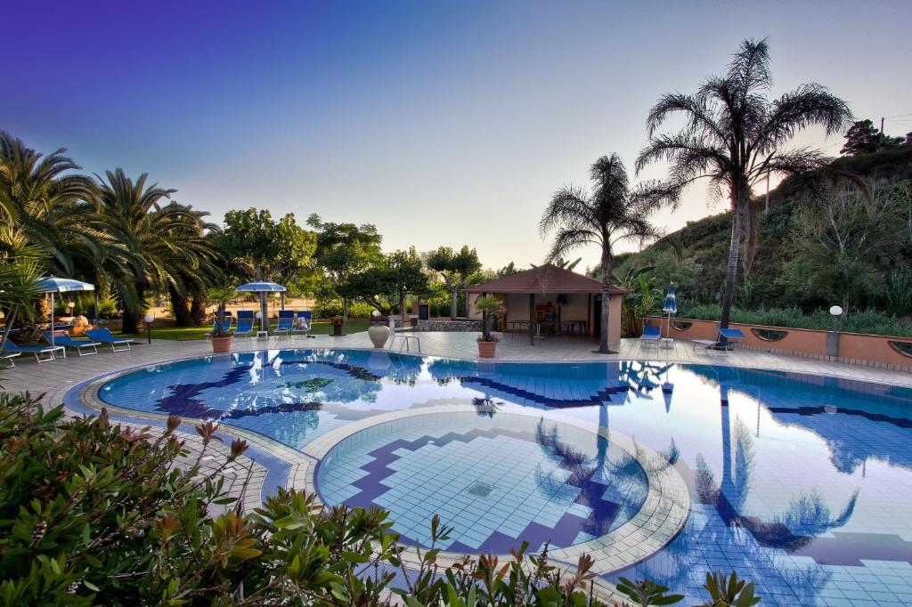 梵蒂冈角Hotel Villaggio Old River的一座拥有蓝色海水和棕榈树的大型游泳池
