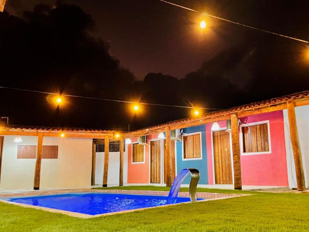 佩德拉斯港Pousada Ventos e Velas的一座晚上设有游泳池的房子