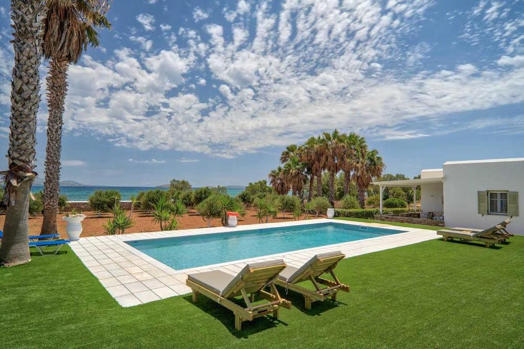 安迪帕罗斯岛Sunrise Luxury Apartments & Suites的一个带两把椅子的游泳池以及一座房子