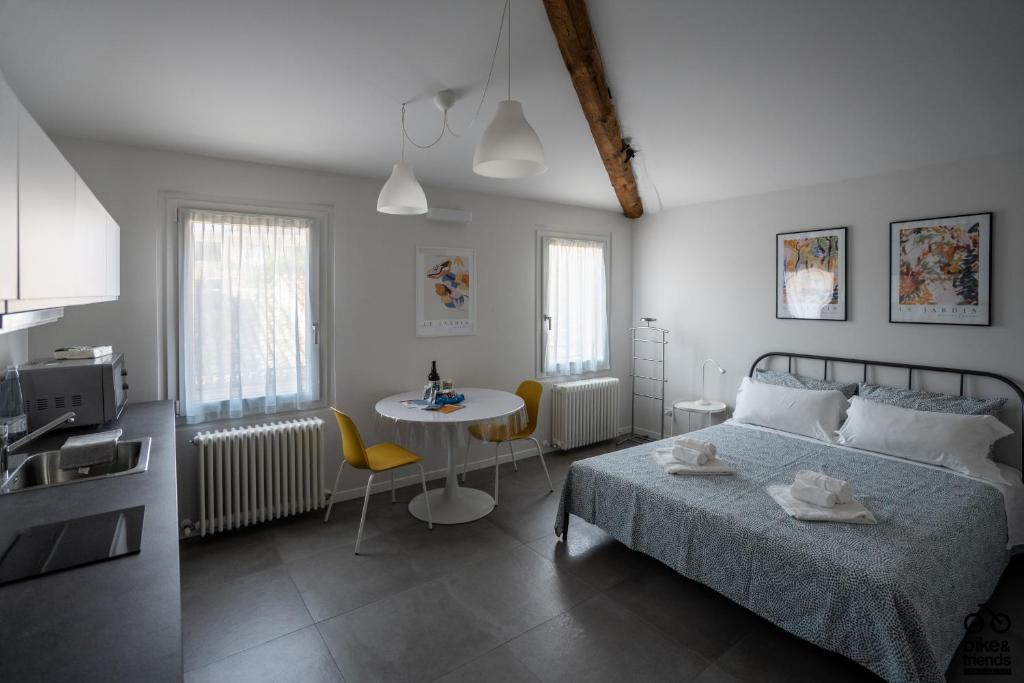 佩萨罗MONOLOCALE LE RONDINI centralissimo的一间卧室配有一张床铺和一张桌子,还设有一间厨房
