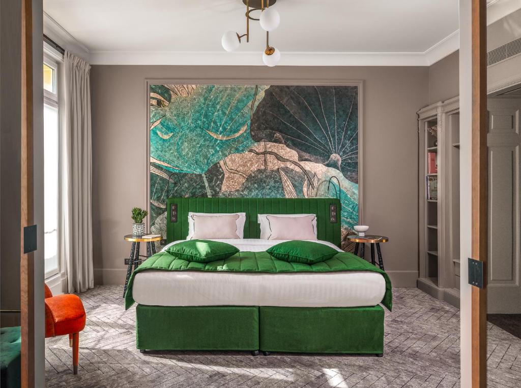 巴黎M Social Hotel Paris Opera的卧室配有一张绿色的床,墙上挂有绘画作品