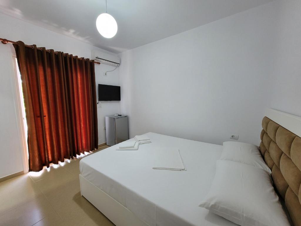 卡萨米尔Vila Geri的卧室配有白色的床和红色窗帘