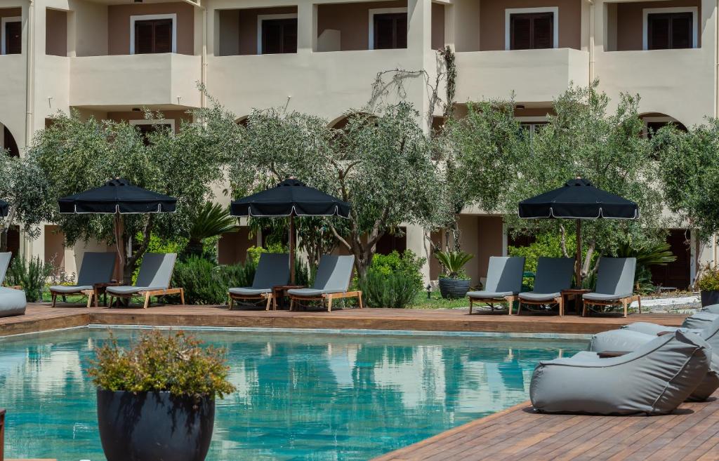 卡拉马孔Bitzaro Palace Hotel的酒店游泳池设有椅子和遮阳伞