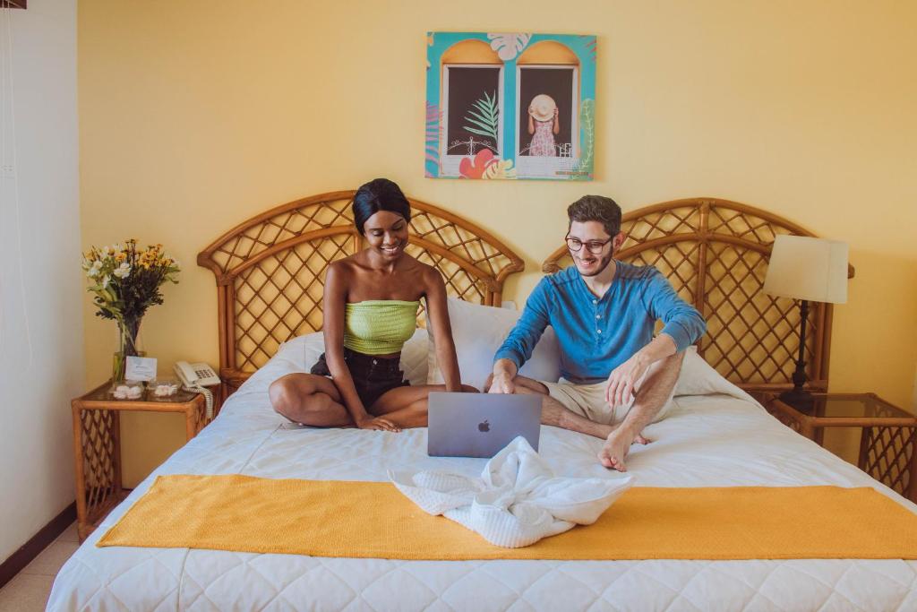 弗洛勒斯桑塔纳酒店的坐在床上的男人和女人,手提电脑