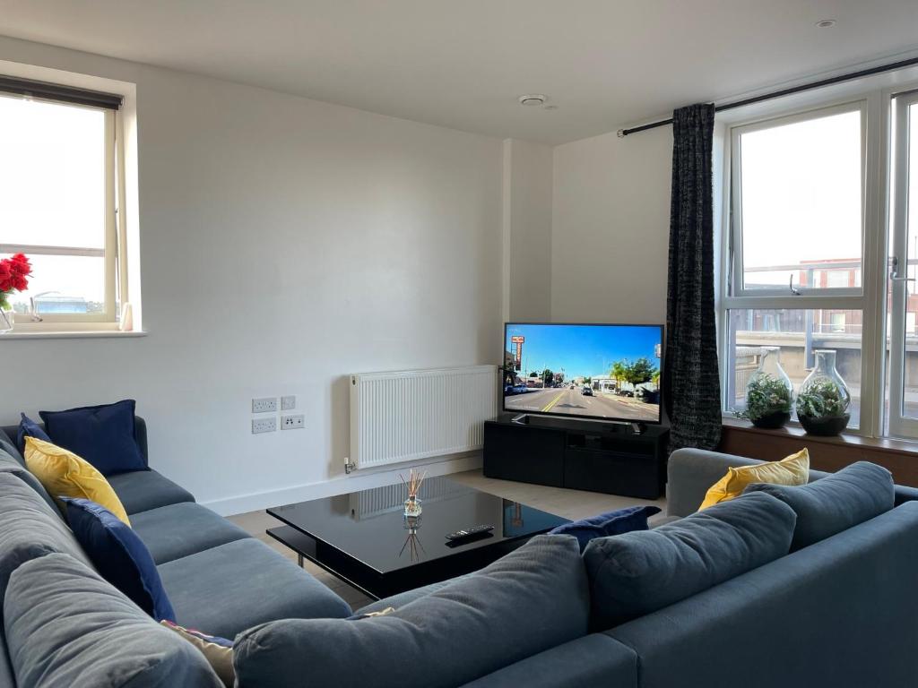 伦敦Modern & Spacious Penthouse in North London的客厅配有蓝色的沙发和电视