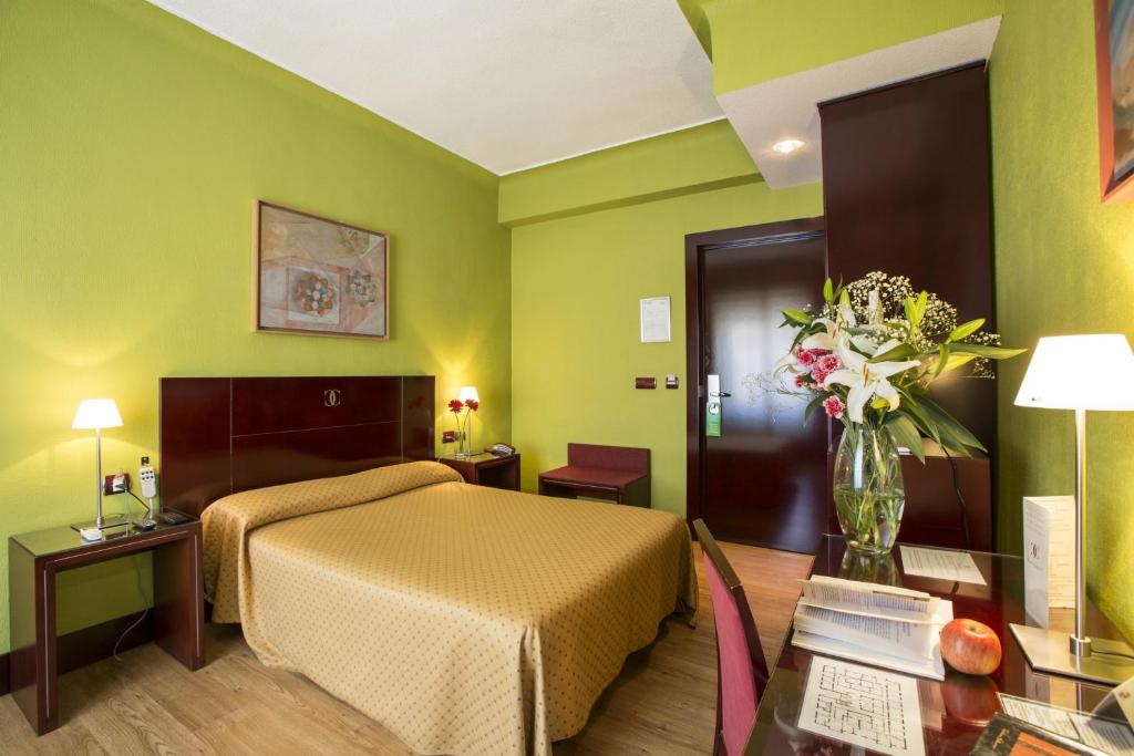 格拉纳达Hotel Carlos V的配有一张床和花瓶的酒店客房