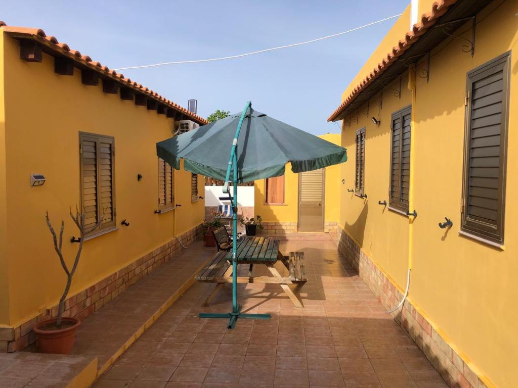 兰佩杜萨Villette ad uso turistico Lampedusa的蓝色的伞,坐在黄色的建筑旁边