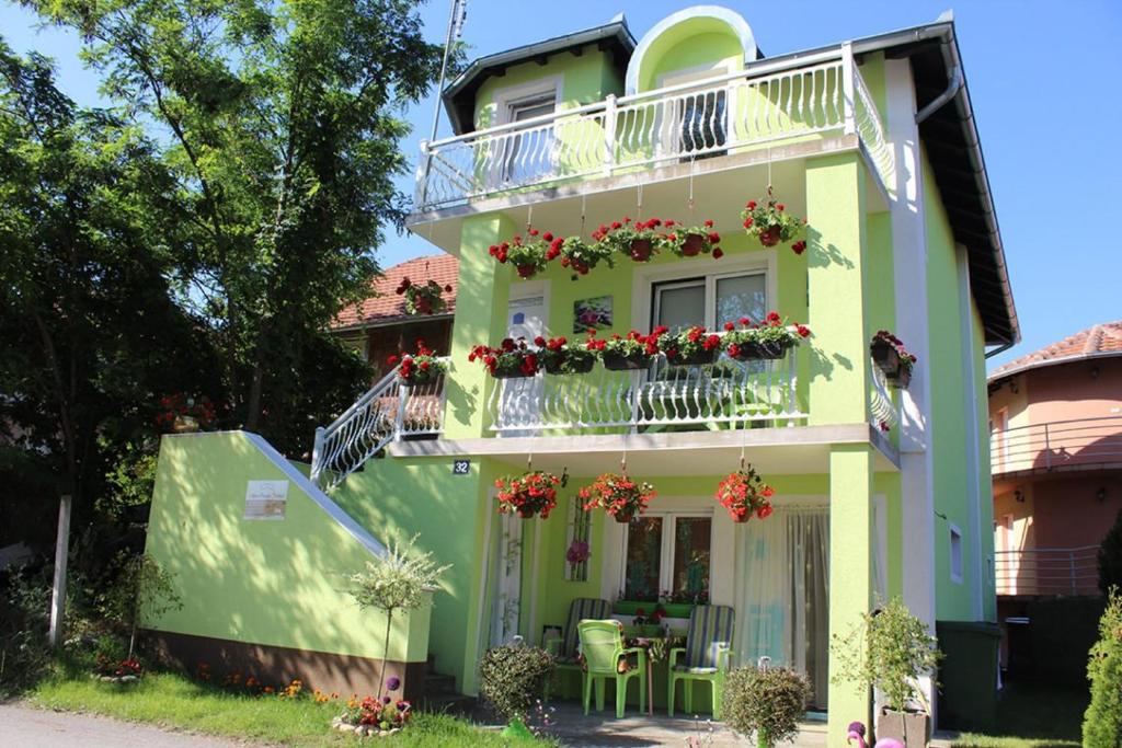 大格拉迪什泰Apartmani Cirkov的绿色的房子,带鲜花的阳台