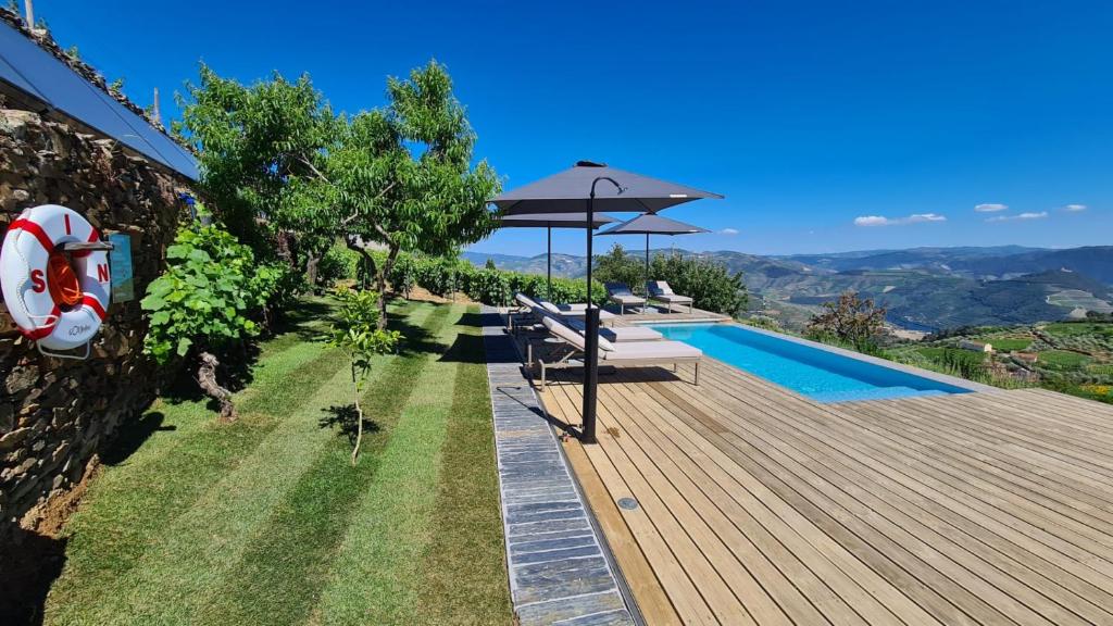 ProvesendeCasa de Pena d'Águia - Douro Encantado的游泳池旁带遮阳伞的木甲板