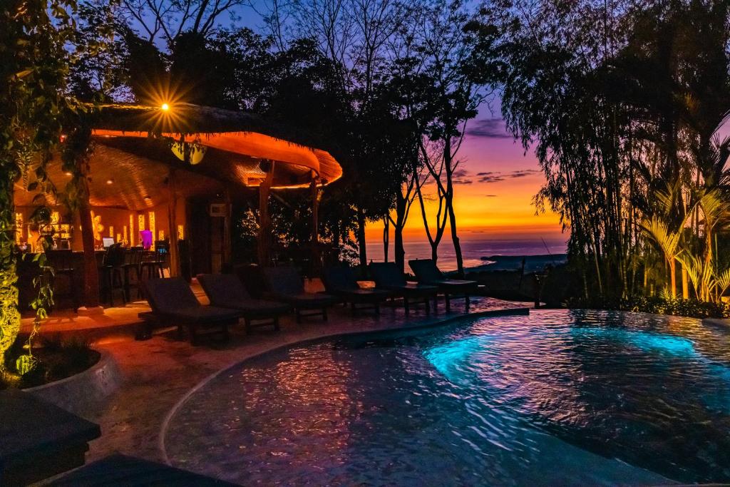 乌维塔Selva Armonia Immersive Jungle Resort的一个带椅子的游泳池,享有日落美景