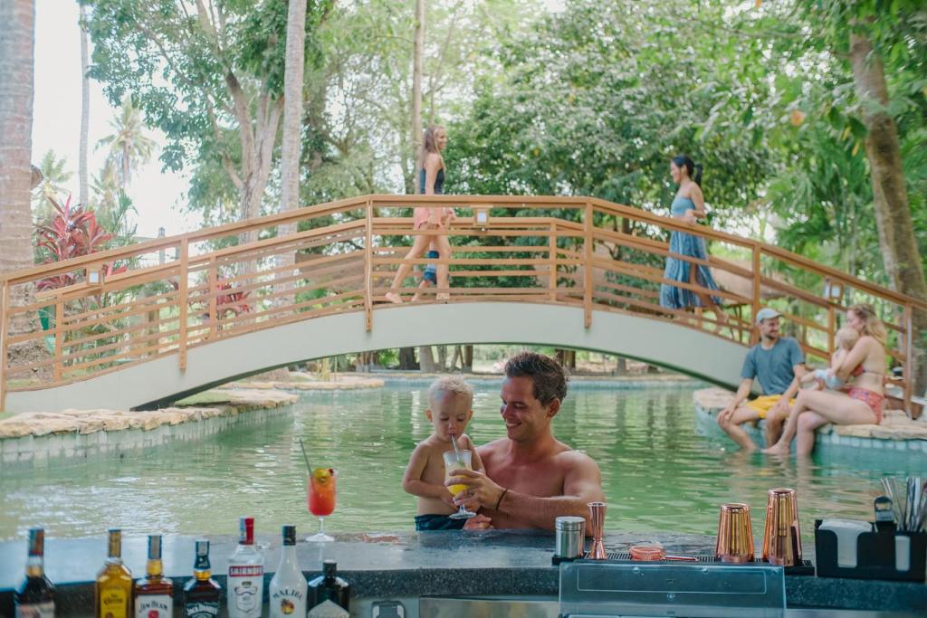 塞隆贝拉纳克Tropik Resort Lombok的桥下水中的男人和孩子