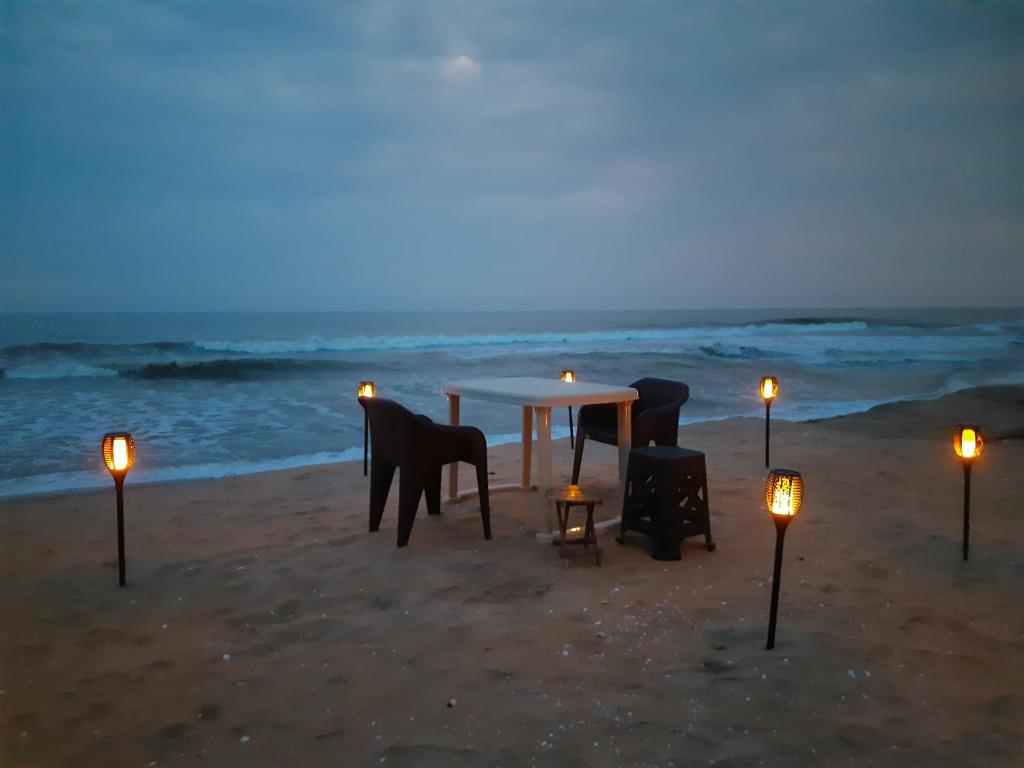 PayyannūrThe Camp Club Beach Villa的海滩上的一张桌子和椅子