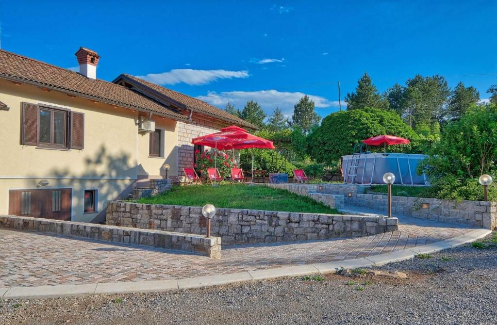 迪瓦查Počitniška hiša Miklavčič Primorska的院子里有两把红伞的房子