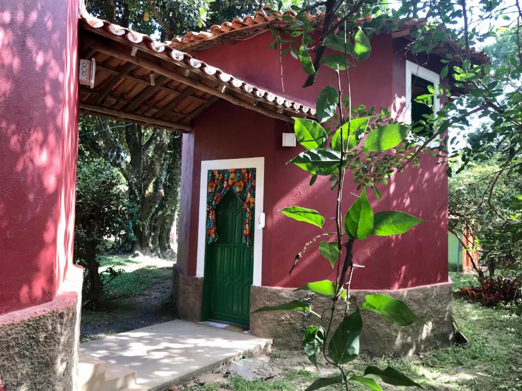 韦尔卡鲍Chalé Raio De Sol的一座红色的房子,有绿门和一棵树