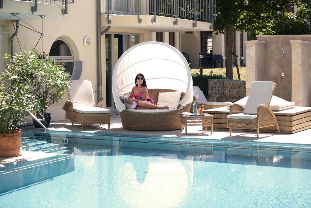 黑灵斯多夫黑灵斯多夫斯丹德酒店的坐在游泳池旁的泡泡椅上的女人