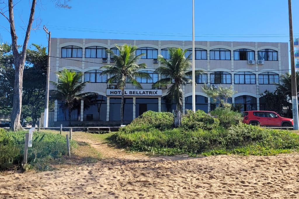 马卡埃贝拉特里克斯酒店的海滩上的一座建筑,前面有棕榈树