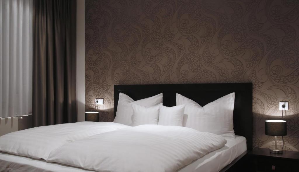 Wehrheim莱姆斯酒店的一间卧室配有带白色床单和枕头的床。