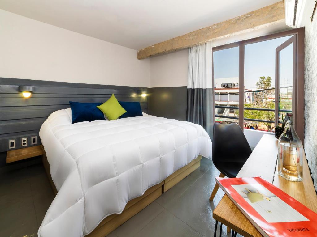 瓜达拉哈拉Hotel NEXT的卧室配有一张白色大床和一张书桌