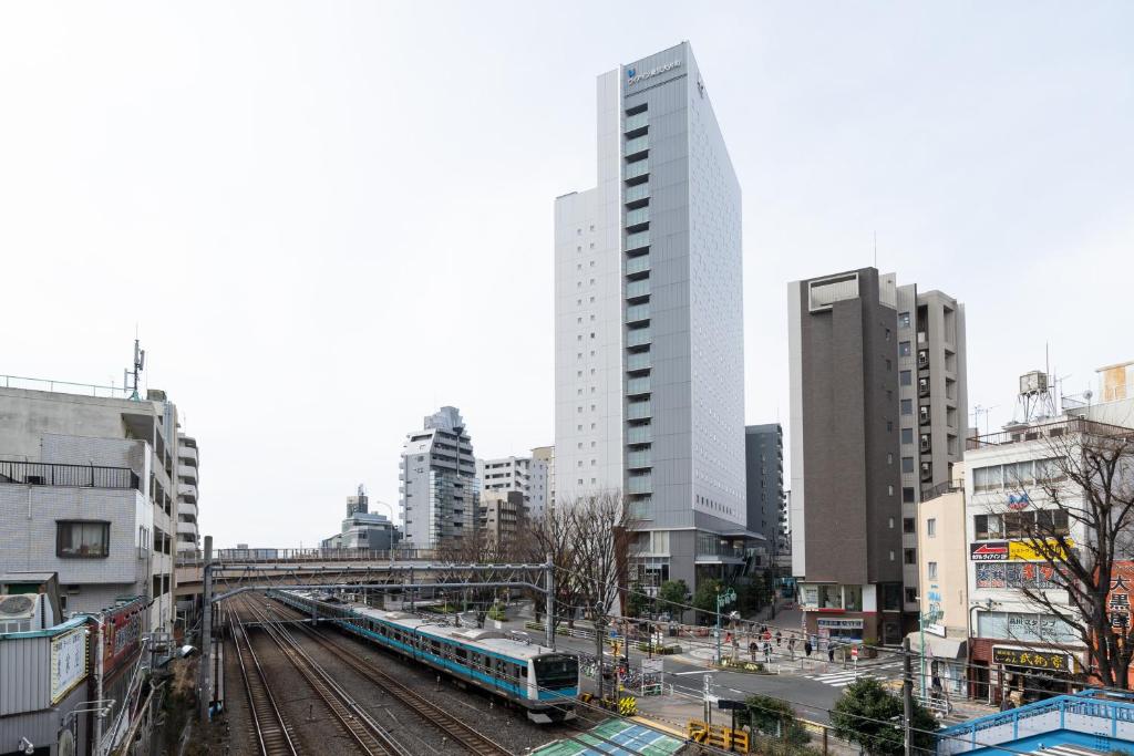 东京Via Inn Shinagawa Oimachi的城市中拥有建筑物的轨道上的火车