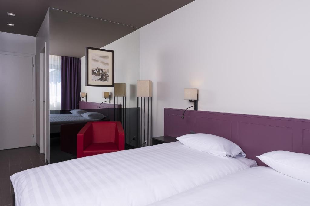日内瓦Hôtel Les Nations的酒店客房,设有两张床和一张红色椅子