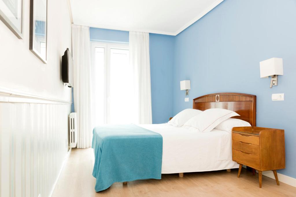 萨拉戈萨索斯酒店的卧室配有白色的床和蓝色的墙壁