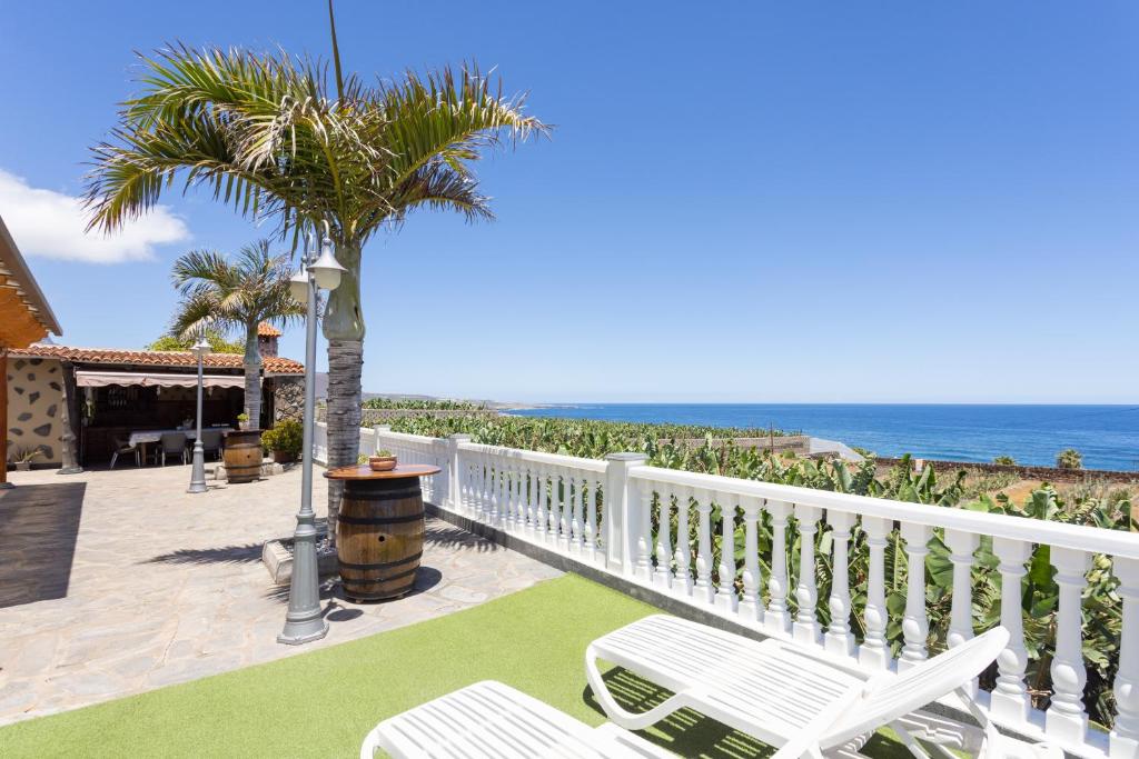 Las CrucesHome2Book Garachico Ocean View的阳台配有椅子、棕榈树和海洋