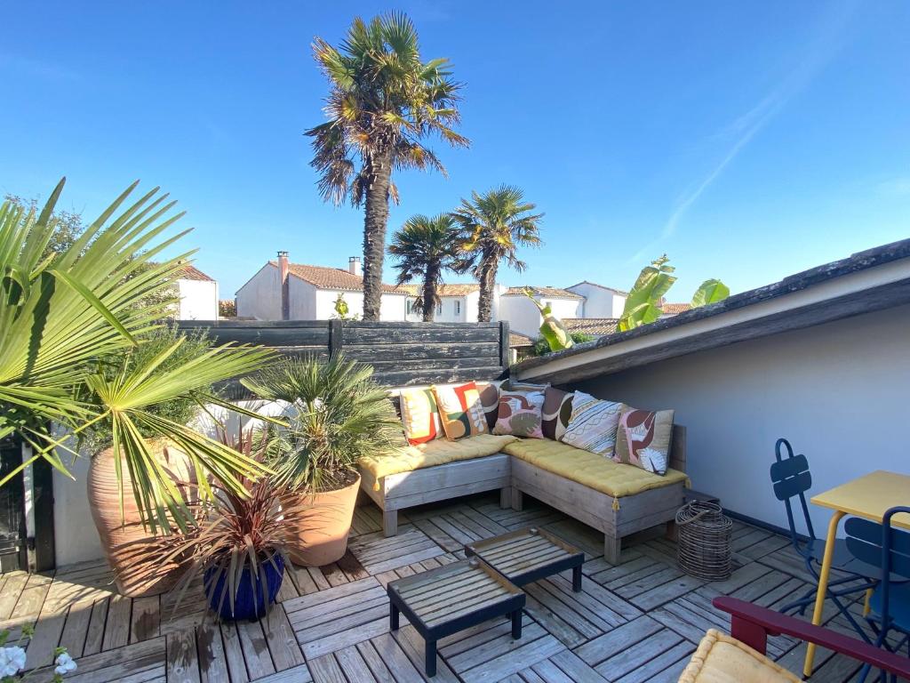 雷岛林滩La Terrasse du Bois Plage的一个带沙发和棕榈树的屋顶庭院