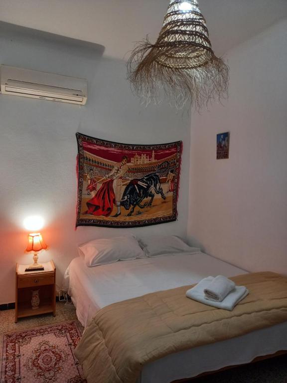 哈曼苏斯Dar Hkaïem的卧室配有一张床,墙上挂着挂毯