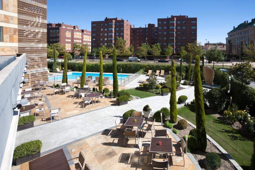 巴利亚多利德Sercotel Valladolid的一个带桌椅的户外庭院和一个游泳池