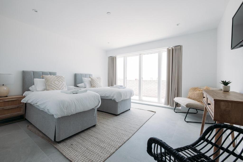 纽基NEW Luxury Coastal Apartment with vast sea views的一间卧室配有两张床、一张桌子和一把椅子