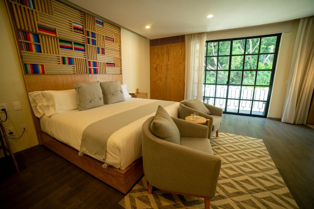 瓜达拉哈拉Hotel Dex Tlaquepaque的一间卧室配有一张大床和两把椅子