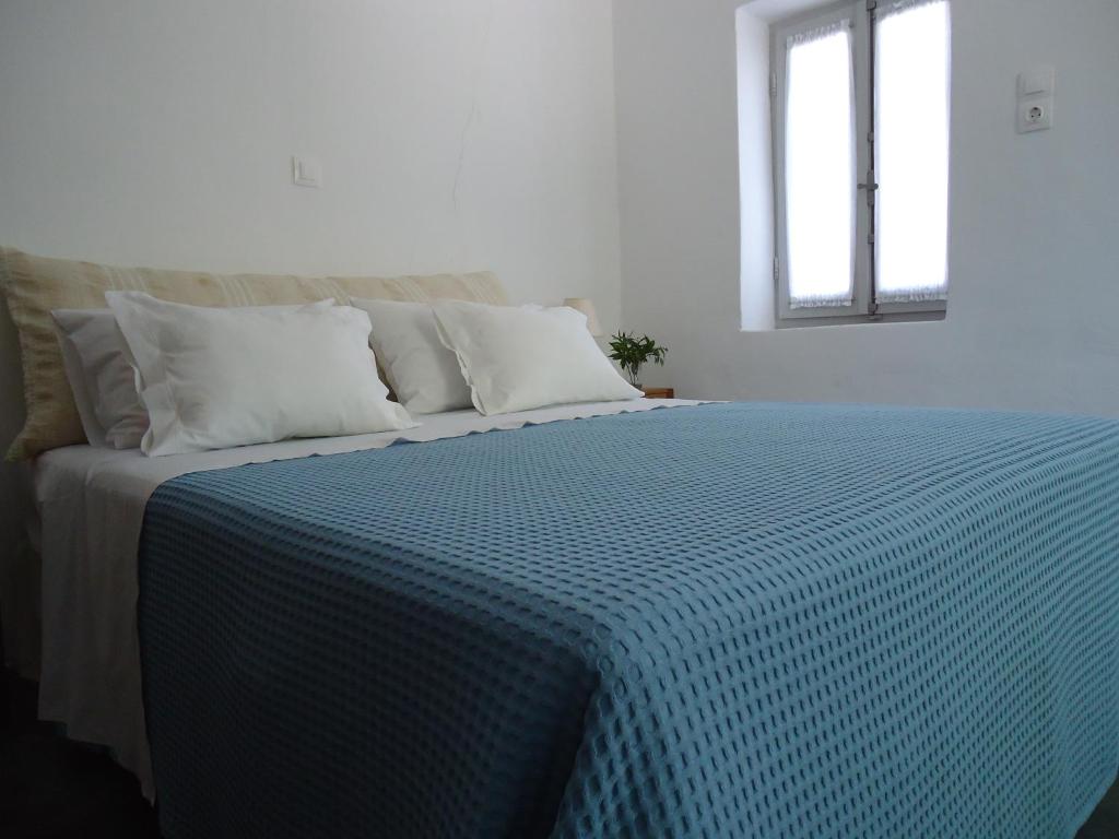 KórinthosAνεξάρτητη παραδοσιακή πέτρινη κατοικία的一张带蓝色和白色棉被的床和一个窗口